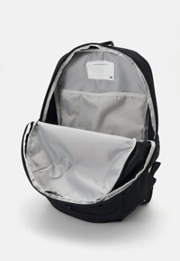 Black backpack with a gray interior. Features a large main compartment, a flat pocket inside, and durable fabric. Zippered closure.