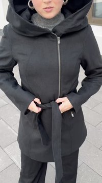 Casaco preto, com fecho zip e uma grande capuz, cintura com cinto e bolsos. Tecido texturizado com um acabamento suave, ideal para climas frios.