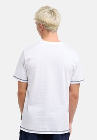 Weißes Kurzarm-T-Shirt aus Baumwolle. Mit Kontrastnähten am Kragen und an den Ärmeln sowie einer lässigen Passform. Schlichte Rückansicht.