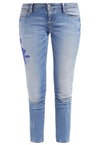 Světle modré skinny džíny s vybledlými oblastmi, ozdobené modrým květinovým vyšíváním na levé noze, s klasickým designem pěti kapes.