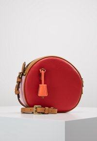 Okrągła torba na ramię wykonana z czerwonej skóry z jasnym wnętrzem. Posiada jasnobrązowy pasek i pomarańczowy suwak z dodatkami w kolorze złota.