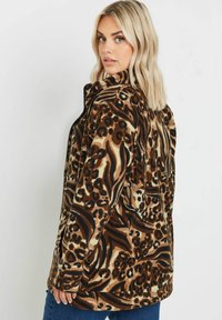 Fleecetröja med ett brunt och beige abstrakt djurmönster, dragkedjestängning, ståkrage och sidofickor. Mjuk textur och avslappnad passform.