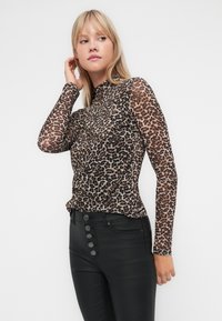 Leopardenprint lange mouwen top gemaakt van transparante stof, met een hoge halslijn en een getailleerd ontwerp. Gecombineerd met zwarte hoge taillebroek.