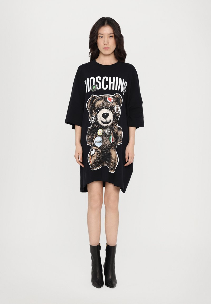 Μαύρο υπερμεγέθες φόρεμα μπλούζα με γραφικό αρκούδας, πολύχρωμα σήματα και λογότυπο "Moschino" στην κορυφή. Λείο βαμβακερό ύφασμα.
