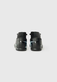 Chaussures de sport noires avec un design montante, en matériau texturé, avec des accents bleu clair contrastants et une semelle en caoutchouc lisse, vues de l'arrière.
