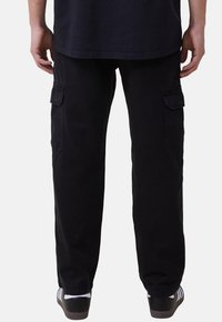 Svarta cargo-byxor med avslappnad passform, med sidofickor, en lätt glans och rak ben-design. Matchas med svarta sneakers.