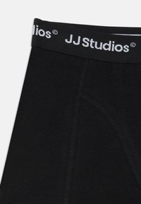 Čierne bavlnené slipy s mäkkým elastickým pásom, na ktorom je biele logo "JJ Studios". Bezšvový predný diel a klasický dizajn.