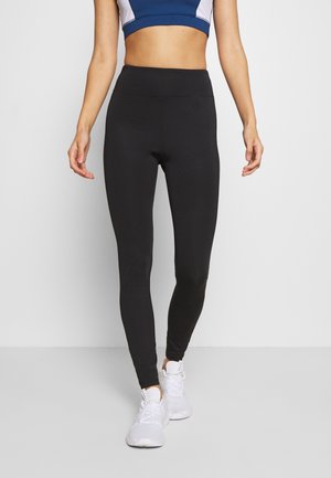 Black leggings made from stretchy material, featuring a high waist design that fits snugly. Paired with white athletic shoes.
