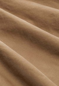 Țesătură texturată, de culoare maronie, cu o suprafață netedă și un model geometric subtil, pliată pentru a arăta adâncimea și nuanțele variate de culoare.
