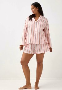 Lyserødt pyjamassæt med striber, bestående af en skjorte med knapper og lange ærmer samt matchende shorts, begge med kontrasterende orange striber. Tekstureret stof.