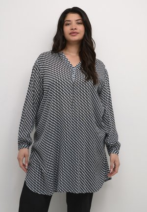 Bluză lungă cu model alb-negru, decolteu în V, cu accente din nasturi, croi lejer și mâneci lungi, având un design geometric cu diamante.