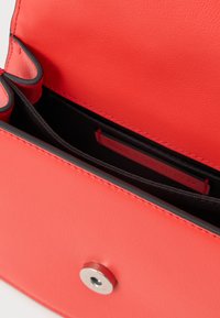 Rode leren tas met een binnenvak van zwarte stof en een zilveren magneetsluiting, van bovenaf opengetoond.