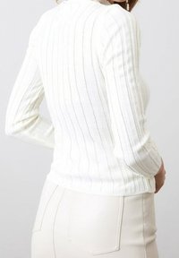Witte geribde trui met lange mouwen, met een aansluitend ontwerp en gestructureerde lijnen. Gepaard met een lichte, aansluitende rok.