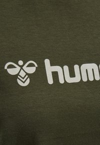 Tessuto verde oliva con un logo grafico bianco che rappresenta un'ape e la parola "human" in carattere grassetto, con una consistenza liscia.