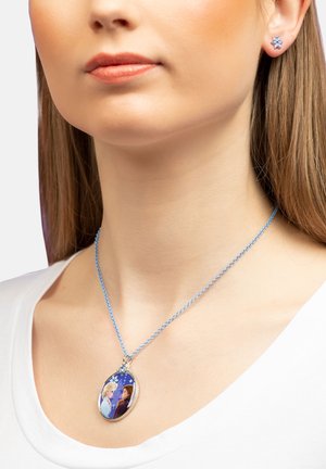 La collana a catena blu presenta un pendente ovale con un'illustrazione di due personaggi su uno sfondo blu. Sono visibili dettagli in metallo tono argento.