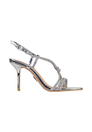 Sandalo argento con tacco alto, sottili cinturini, decorazioni con strass, fibbia alla caviglia e tacco a spillo appuntito su sfondo bianco.