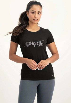 Schwarzes, eng anliegendes T-Shirt mit kurzen Ärmeln. Auf der Brust befindet sich handgeschrieben "namaste" in hellgrauer Schrift. Weiche Stoffstruktur.