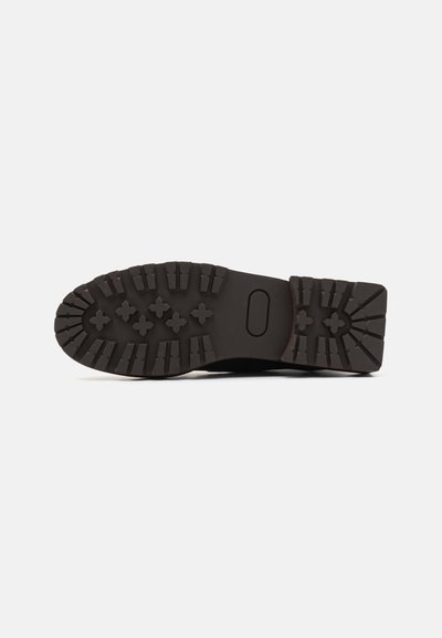 Black rubber shoe sole with a textured, multi-directional tread pattern for grip, featuring a smooth heel and rounded toe design.