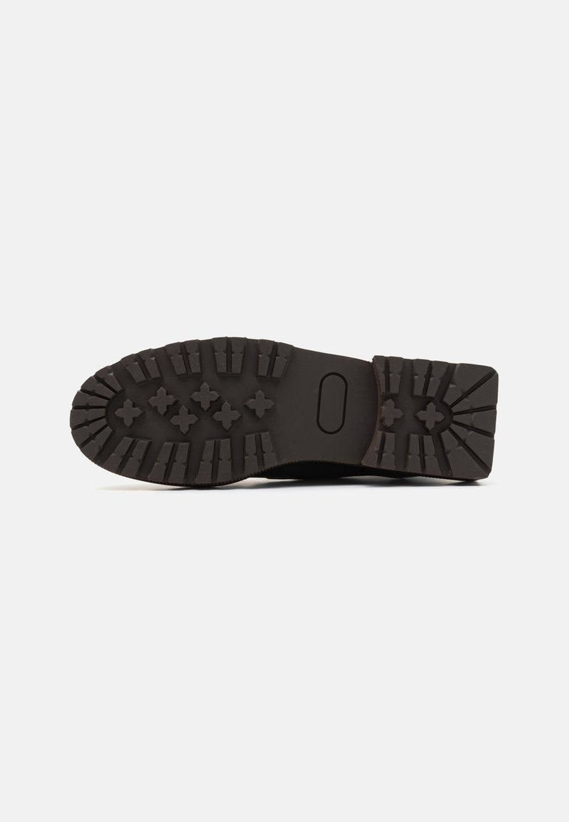 Schwarze Gummisohle mit einem strukturierten, multidirektionalen Profil für Grip, ausgestattet mit einer glatten Ferse und einem abgerundeten Zehendesign.