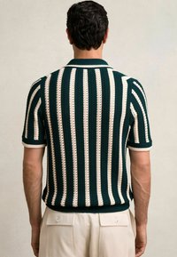 Polo à manches courtes tricoté avec des rayures verticales vertes et crème, un motif texturé et un col et des poignets côtelés.