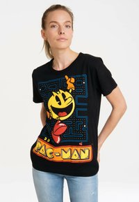 Black cotton t-shirt featuring a large, colorful Pac-Man graphic with a maze design. The shirt has a round neck and short sleeves.