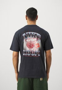 Czarny bawełniany T-shirt z kolorowym nadrukiem koszykówki na plecach oraz napisem "NIKE HOOPS SUMMER LEAGUE", krótkimi rękawami i luźnym krojem.