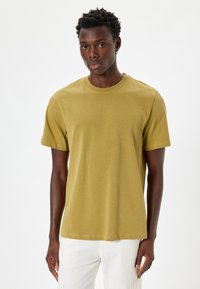 Oliven grøn t-shirt med korte ærmer og rund halsudskæring, glat tekstur og regular fit, præsenteret mod en ensfarvet hvid baggrund.
