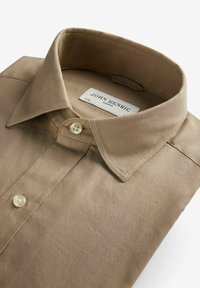 Beige skjorta med krage, tillverkad av bomullstyg, med en mjuk yta, knappstängning fram och en etikett med märket "John Henric" sydd inuti.