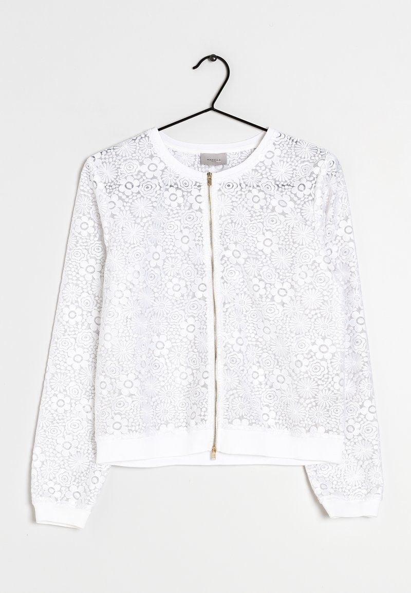 Biała bluza z suwakiem, pokryta koronką w kwiaty, z długimi rękawami, ściągaczami przy rękawach i u dołu oraz złotym zamkiem błyskawicznym. Zaprojektowana z minimalistycznymi akcentami.