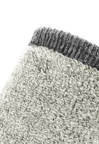 Grau gestrickte Socke mit einer strukturierten Oberfläche und einem gerippten, dunkelgrauen Bund. Der Körper hat ein weiches, flauschiges Aussehen, das Wärme bietet.