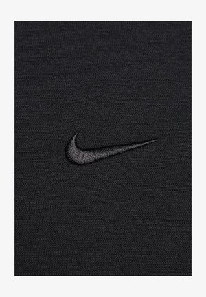 Tecido preto com um ponto texturizado; apresenta um logo bordado da Nike em preto igual.