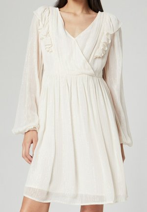 Witte jurk met lange mouwen, gerimpelde schouders en een V-hals. Gemaakt van gestructureerde stof met subtiele glans en een uitlopende rok.