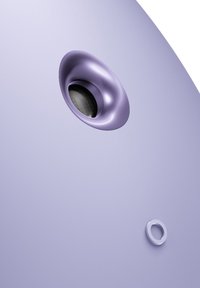 Haut-parleur violet avec une finition mate lisse. Présente une grille noire circulaire et un petit détail en anneau blanc. Design arrondi et épuré.