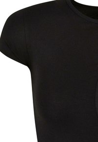 Gros plan d'un t-shirt noir à manches courtes montrant l'encolure ronde et le haut de l'épaule.