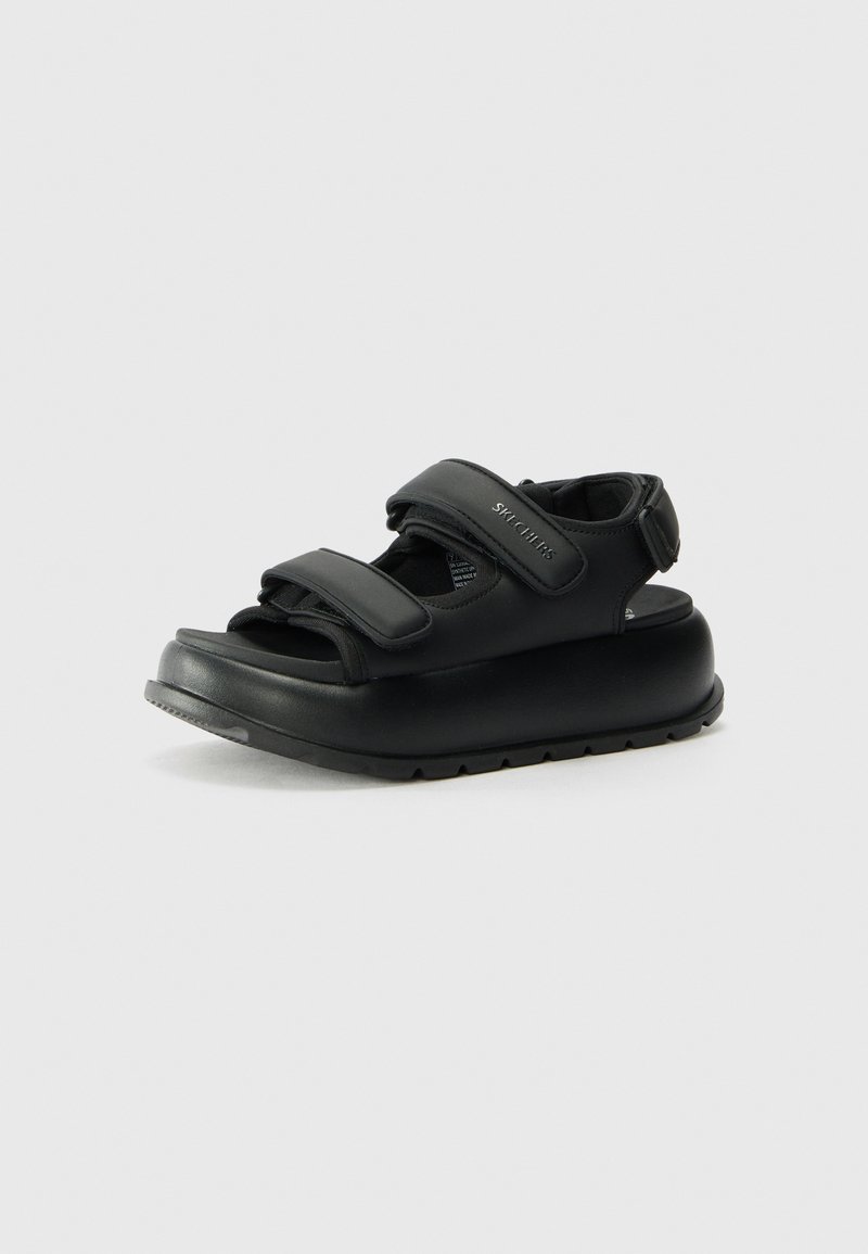 Schwarze Sandalen mit einer robusten Sohle, offenem Design und verstellbaren Klettverschlüssen für einen sicheren Sitz. Glatte Textur mit minimalistischer Markenkennzeichnung.