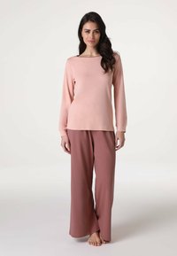 Set di pigiama composto da una maglietta a maniche lunghe di un rosa chiaro con scollo a barca e pantaloni ampi e larghi di un rosa più scuro. Tessuto morbido e liscio.