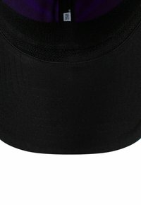 Schwarze Baseballkappe mit lila Innenfutter und einem sichtbaren weißen New Era Etikett auf der Innenseite hinten.