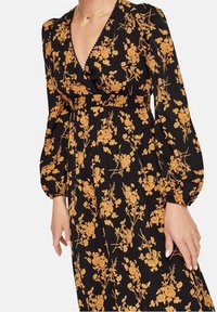 Svart klänning med långa puffärmar och gulblommig dekor, med V-ringning och rynkad midja.