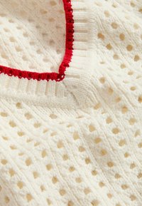 Maglione a maglia crema con design a reticolo aperto, dotato di collo a coste rosso. Texture morbida, sensazione leggera e dettagli di cucitura visibili.