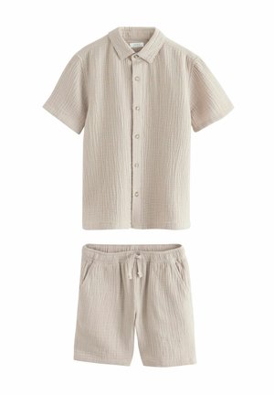 Chemise beige texturée à manches courtes avec boutons, associée à un short à cordon de serrage assorti, tous deux fabriqués en tissu léger.