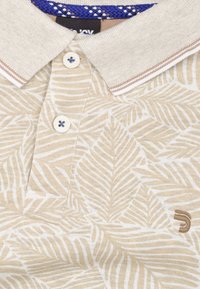 Beige poloshirt met witte bladerenpatronen, een klassieke kraag en drie knopen. Heeft een bruine accent op de kraag en een logo aan de zijkant.