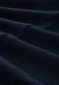 Tissu bleu marine avec une finition douce et texturée. Le matériau semble avoir un motif côtelé, montrant de douces plis et drapés.
