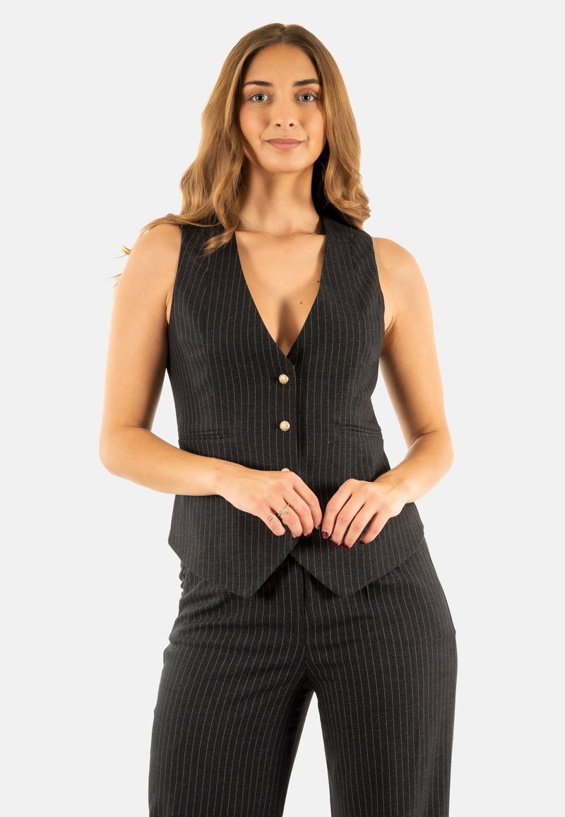 Chaleco negro a rayas con un profundo escote en V, que cuenta con tres botones en el frente y un corte entallado, combinado con pantalones a rayas a juego.