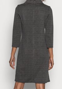 Gray checkered dress with a high collar, three-quarter sleeves, and a fitted silhouette. Features a textured fabric and subtle color variation.