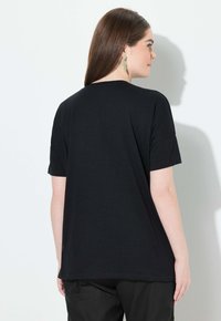 Camiseta negra de manga corta con un ajuste holgado, hecha de una tela suave y texturada. Presenta un sencillo escote redondeado.