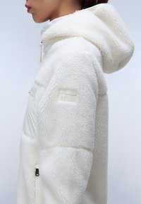 Witte fleece hoodie met een gestructureerd oppervlak, voorzien van een gladde voorkant, een capuchon met trekkoord en een geborduurd logo op de arm.