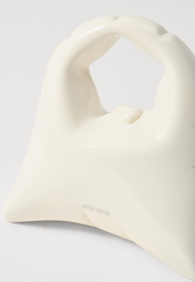 Skinnende hvid håndtaske med et afrundet håndtag, der har et glat, skulptureret design og en lille knaplukning. Graveret med "cult gaia."