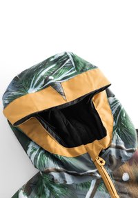 Hættetrøje med et camouflagemønster med palmeblade i grønne og brune nuancer, gule accenter og en sort fleeceforing.