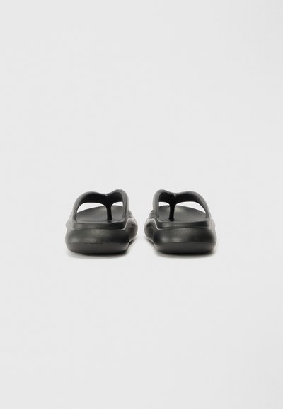 Sandales noires en plastique moulé avec un design ouvert et deux découpes allongées sur le dessus. Texture lisse et mate avec une forme arrondie.