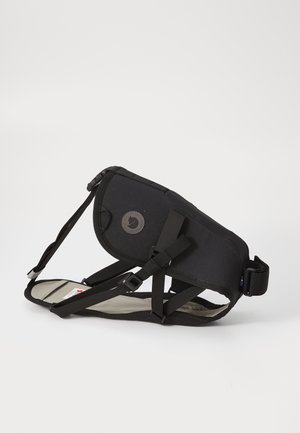 Czarna regulowana uprząż dla psa z bocznym zapięciem, wyściełany pas na klatce piersiowej i plecach oraz okrągłe logo marki na tylnym panelu.